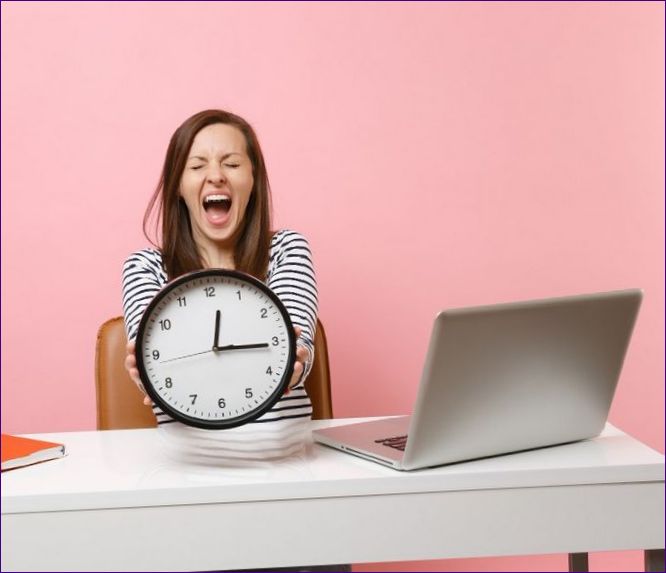 junge-frau-schreiend-um-den-wecker-halten-bei-der-arbeit-am-weissen-schreibtisch-mit-pc-laptop.jpg